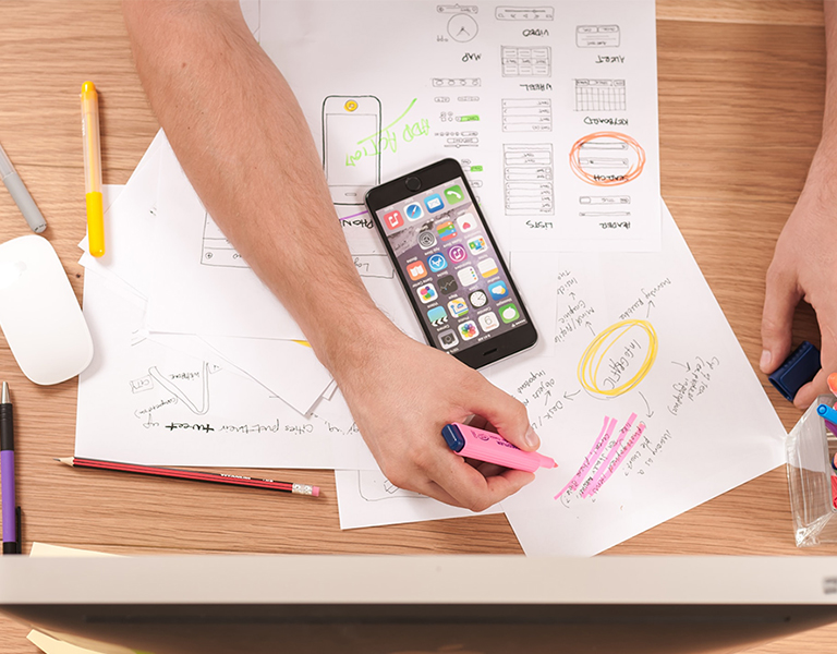 person working at a desk with highlighters and paper