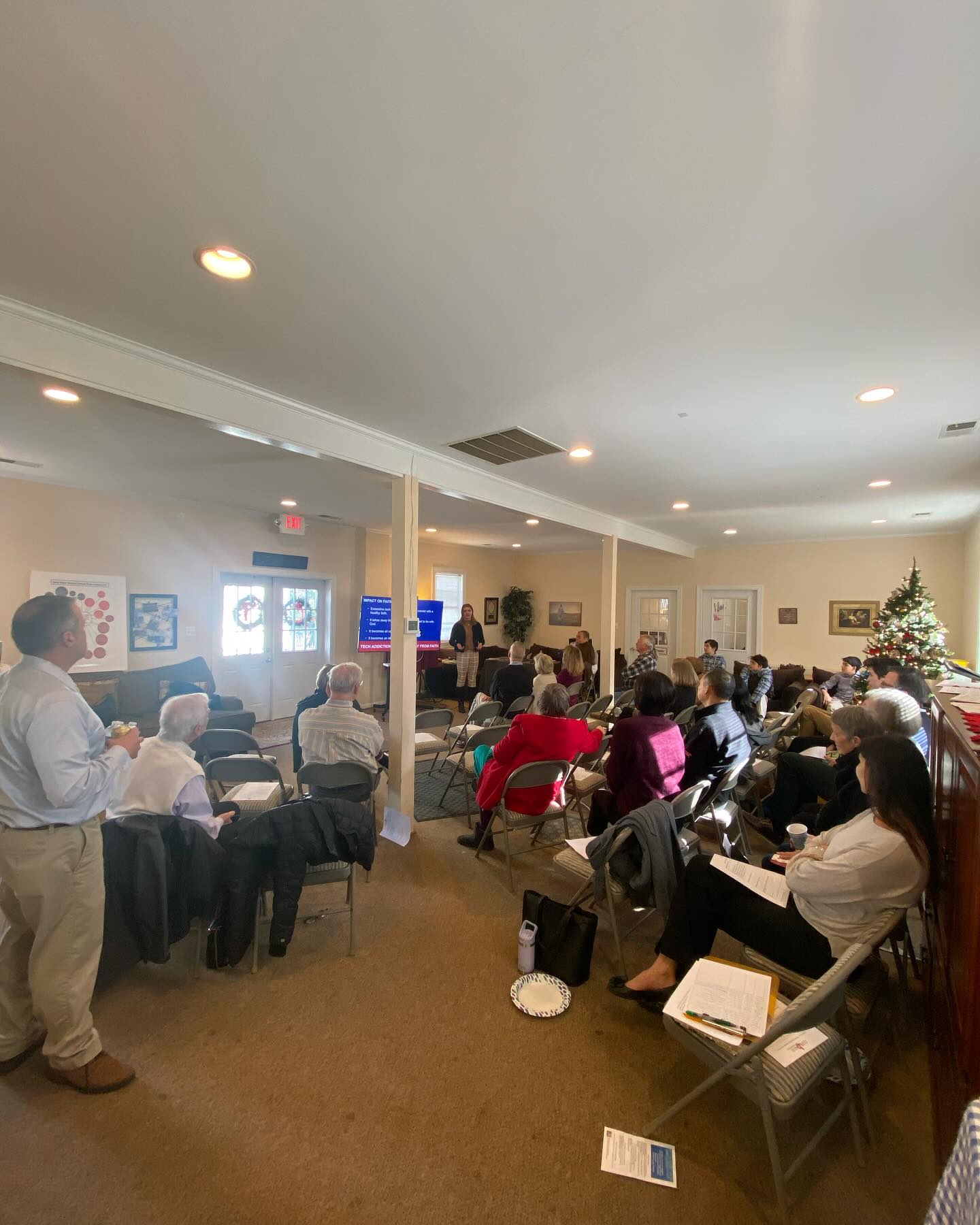 people sitting in a room listening to a speaker