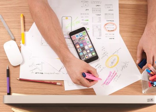person working at a desk with highlighters and a plan